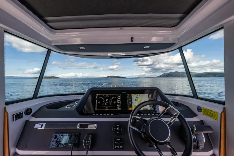 Windermere Yacht Photos Pics Interior view of 2022 Axopar 28 boat cockpit with navigation screens and steering wheel.