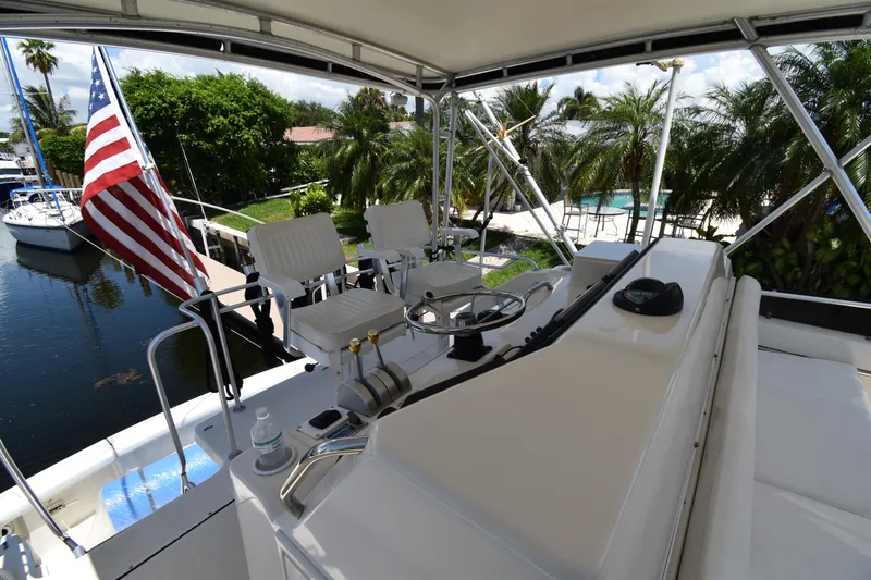  Yacht Photos Pics 1997 Tiara 4300 yacht helm with American flag, docked near lush greenery.
