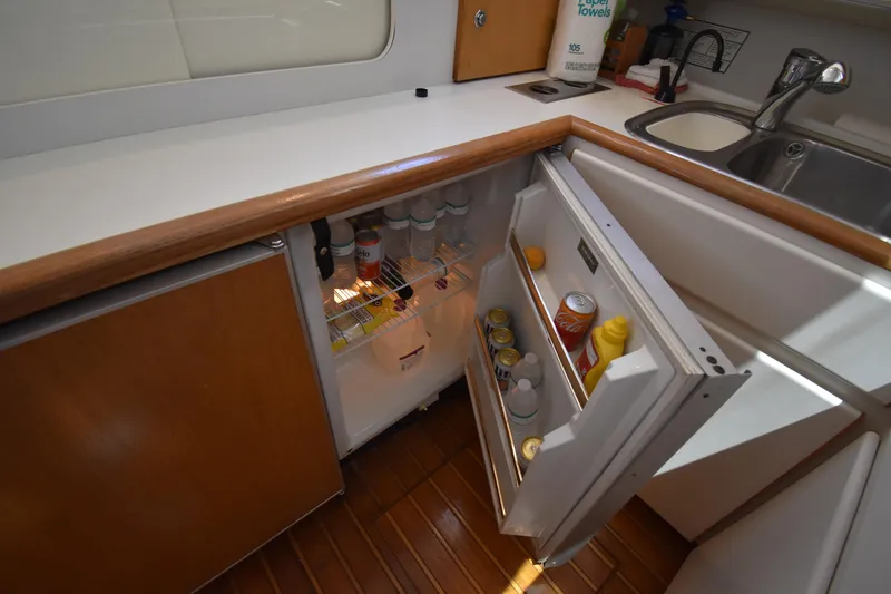  Yacht Photos Pics 1997 Tiara 4300 yacht kitchen with open fridge, wooden cabinets, and sink.
