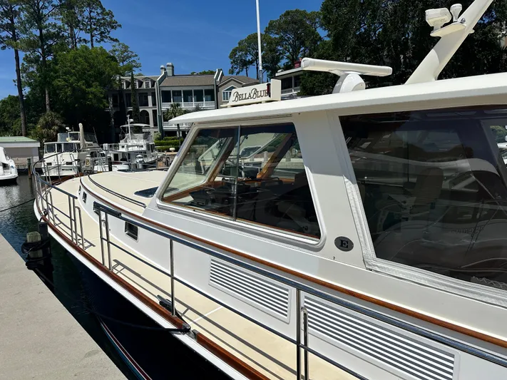 Bella Blue Yacht Photos Pics 2004 Grand Banks 49 Eastbay HX yacht docked at marina, surrounded by trees and buildings.