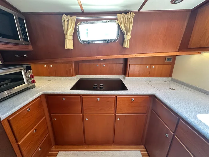 Bella Blue Yacht Photos Pics 2004 Grand Banks 49 Eastbay HX galley with wooden cabinetry, stovetop, and window.