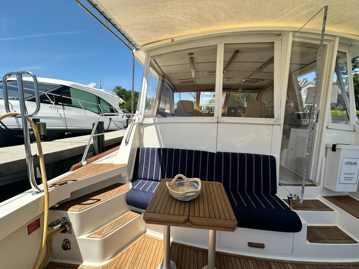 Bella Blue Yacht Photos Pics 2004 Grand Banks 49 Eastbay HX yacht with striped seating and wooden table on deck.