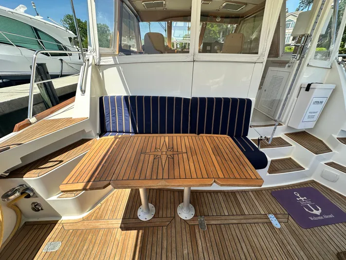 Bella Blue Yacht Photos Pics 2004 Grand Banks 49 Eastbay HX yacht with teak deck, cushioned seating, and wooden table.