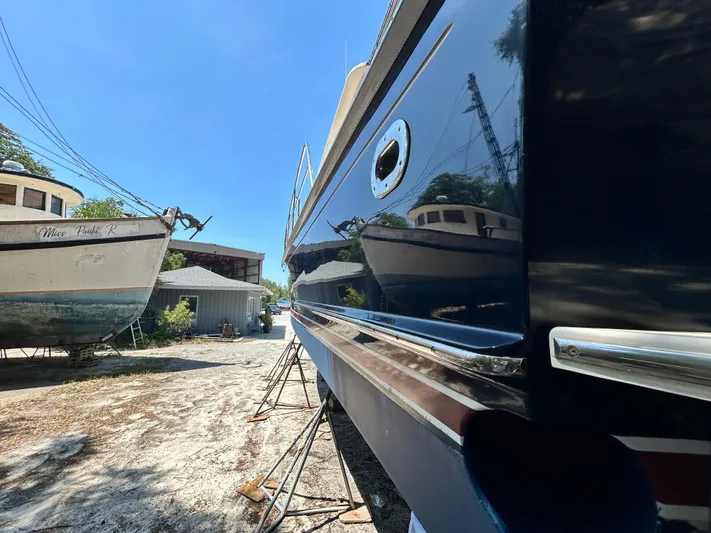 Bella Blue Yacht Photos Pics 2004 Grand Banks 49 Eastbay HX yacht in a boatyard, reflecting nearby vessels.