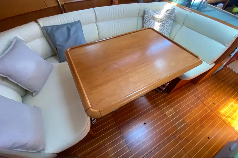  Yacht Photos Pics Cozy interior of 2002 Jeanneau Sun Odyssey 40 with wooden table and cushioned seating.