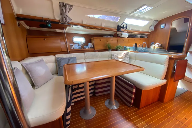  Yacht Photos Pics Interior of 2002 Jeanneau Sun Odyssey 40 sailboat with cozy seating and wooden table.