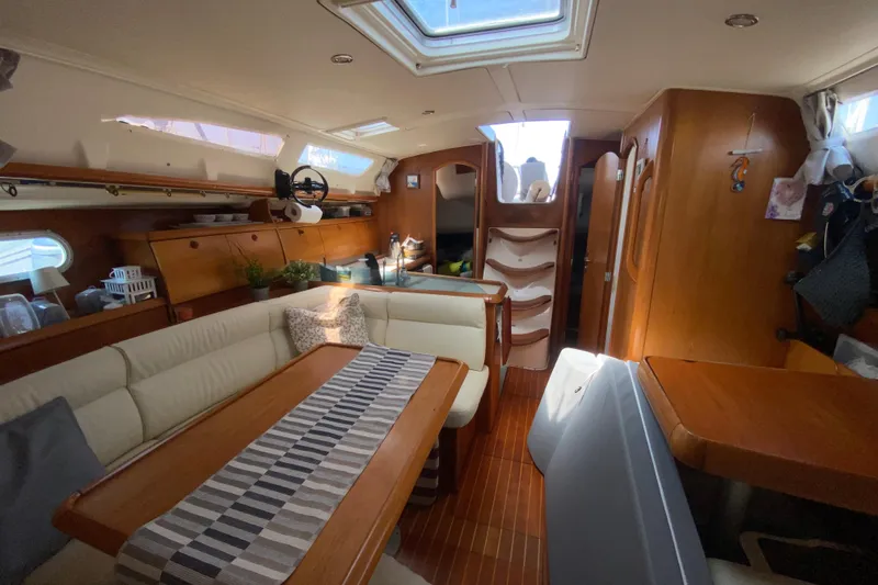  Yacht Photos Pics Interior of 2002 Jeanneau Sun Odyssey 40 sailboat with cozy seating and wooden finishes.