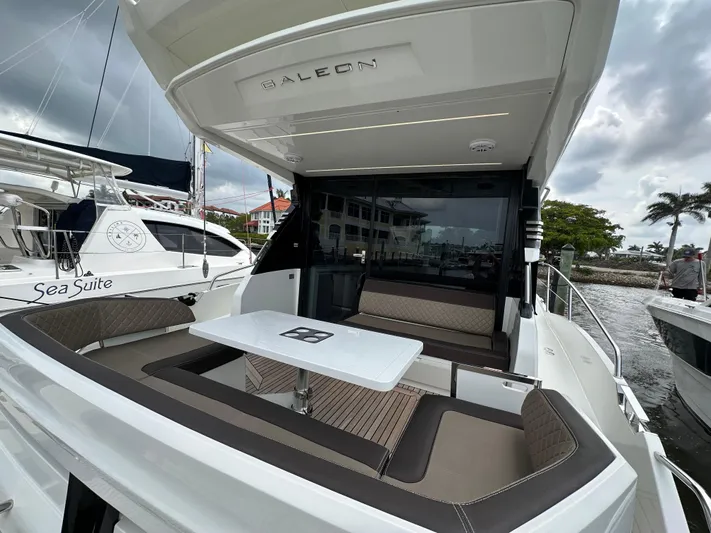 Stelyn Time Yacht Photos Pics Galeon 425HTS 2021 yacht with outdoor seating and table, docked near other boats.