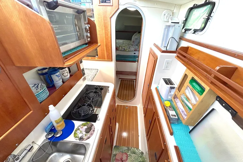 Seahawk Yacht Photos Pics 2004 PDQ 34 Power Catamaran kitchen with stove, sink, and wooden cabinetry.