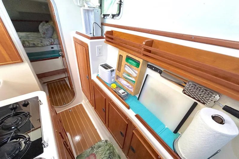 Seahawk Yacht Photos Pics 2004 PDQ 34 Power Catamaran kitchen with wooden cabinets, appliances, and cozy sleeping area.