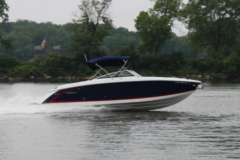  Yacht Photos Pics 2020 Cobalt R30 boat cruising on a calm river with lush green trees in the background.