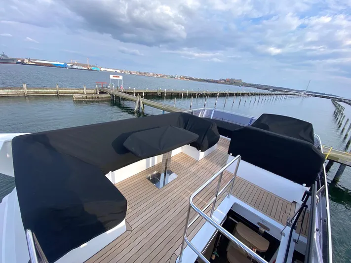 Sealine F430 Yacht Photos Pics 2025 Sealine F430 yacht deck with covered seating, overlooking a serene marina.