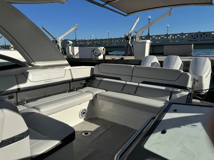 Sunny No Showers Yacht Photos Pics 2023 Formula 350 Crossover Bowrider OB, luxurious seating, docked by a scenic bridge.