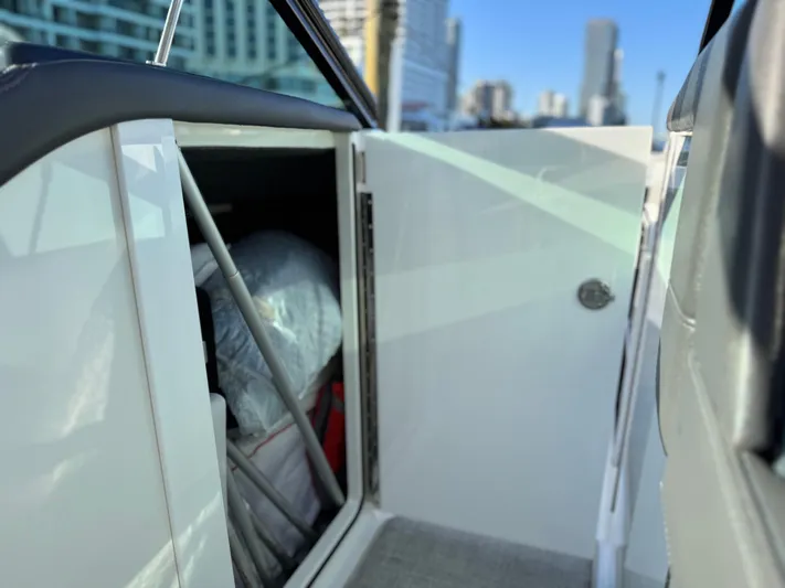 Sunny No Showers Yacht Photos Pics 2023 Formula 350 Crossover Bowrider OB storage compartment with cityscape background.
