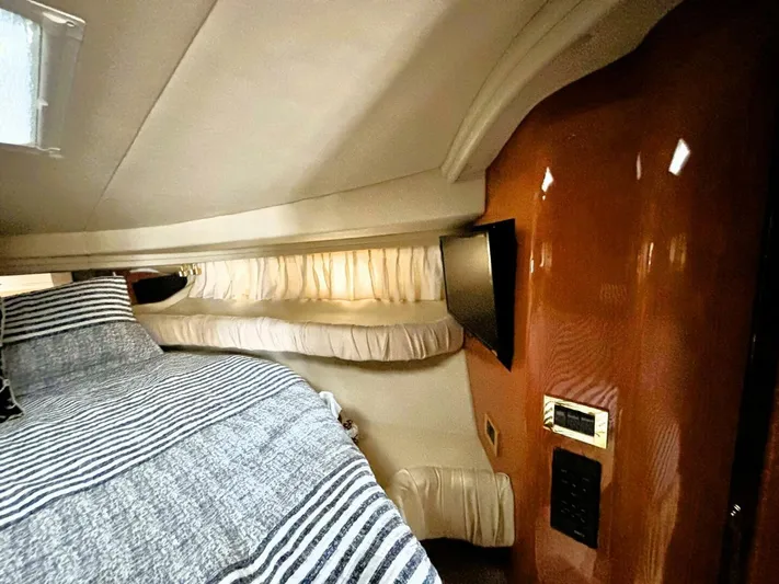  Yacht Photos Pics Interior cabin of 2000 Sea Ray 410 Sundancer with striped bedding and wall-mounted TV.