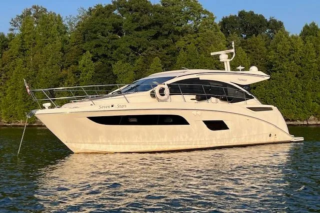 Seven Stars Yacht Photos Pics 2016 Sea Ray 400 Sundancer yacht on calm water, surrounded by lush greenery.