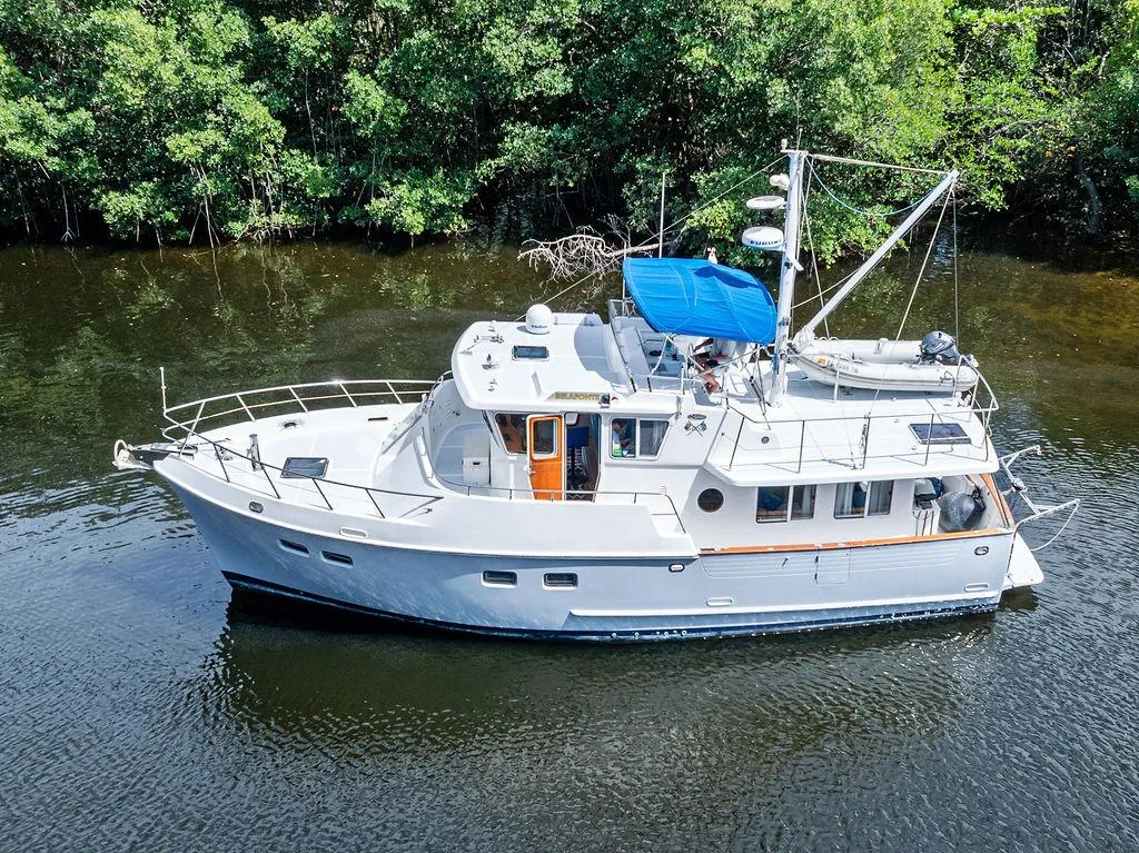 Selene Solo 2000 yacht cruising on a calm river, surrounded by lush greenery.