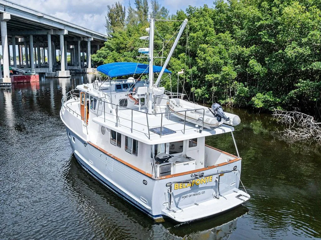 Selene Solo 2000 yacht cruising under a bridge near lush greenery.