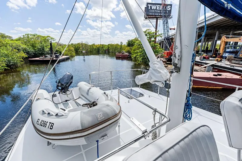  Yacht Photos Pics Selene Solo 2000 yacht with dinghy on deck, docked near lush riverbank and industrial area.