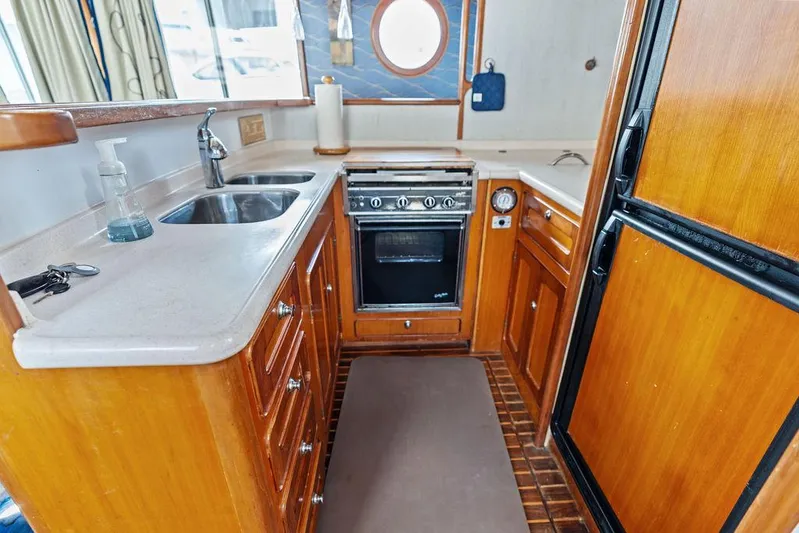  Yacht Photos Pics Compact kitchen in a 2000 Selene Solo boat, featuring wooden cabinetry and modern appliances.