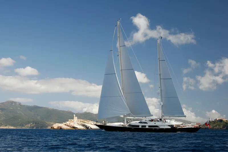 Tamsen Yacht Photos Pics Sailing yacht Perini Navi 52M, 2007, cruising near rocky coastline under clear skies.