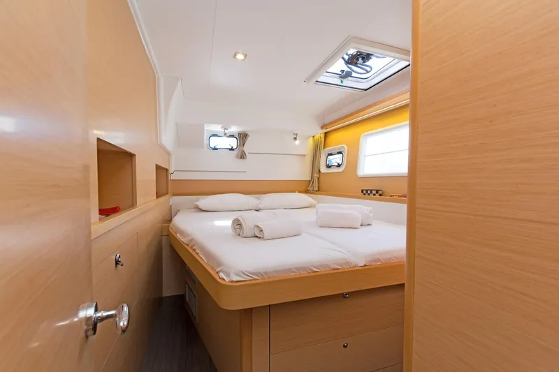  Yacht Photos Pics Cozy cabin interior of 2017 Lagoon 400 S2 catamaran with double bed and porthole windows.