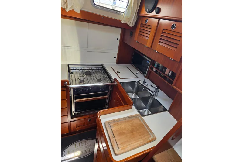 Georgia B Yacht Photos Pics Galley kitchen in 2000 Hallberg-Rassy 42F Mk II yacht with stove, sink, and wooden cabinetry.