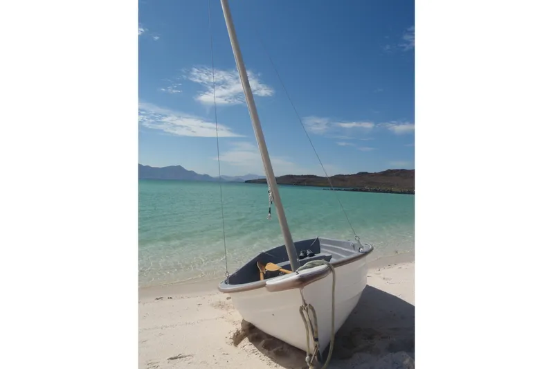 Georgia B Yacht Photos Pics Small sailboat on sandy beach with turquoise water and clear blue sky.