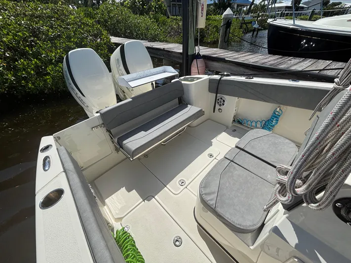  Yacht Photos Pics 2023 Stingray 273 CC boat interior with seating and dual engines at a dock.