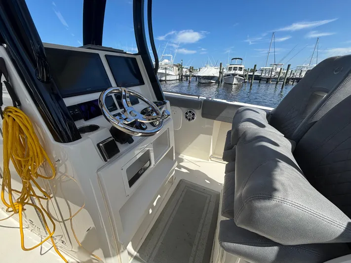  Yacht Photos Pics 2023 Stingray 273 CC boat interior with steering wheel and dual screens at marina.