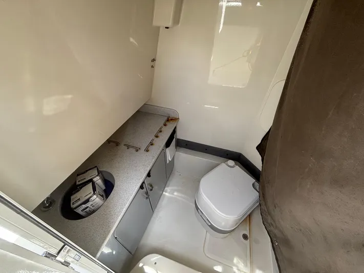  Yacht Photos Pics 2023 Stingray 273 CC boat interior with compact bathroom and storage area.