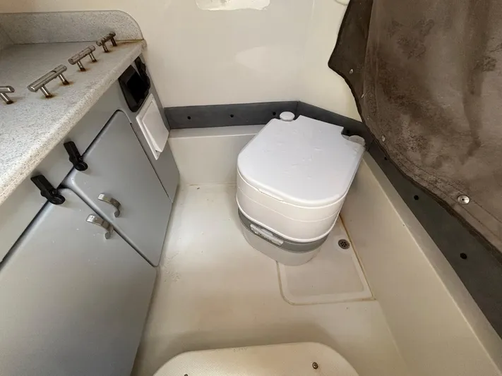  Yacht Photos Pics 2023 Stingray 273 CC boat interior with compact toilet and storage cabinets.