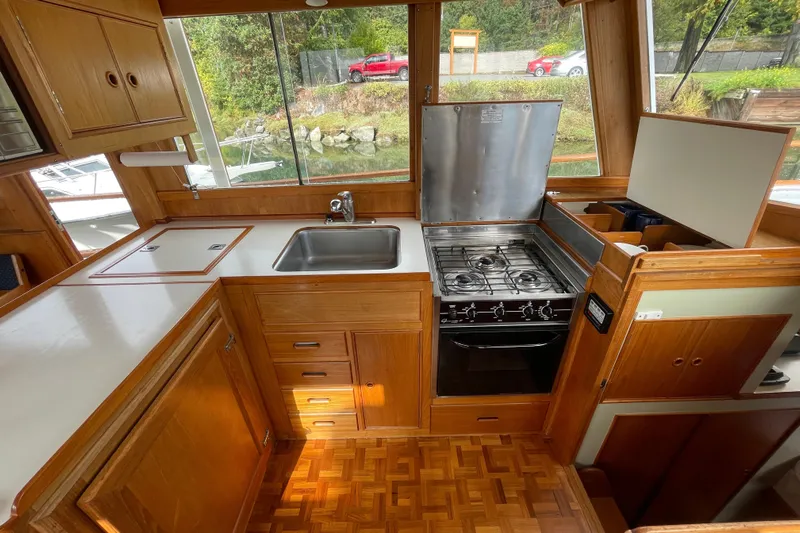 Mercator Yacht Photos Pics 1985 Grand Banks 42 Classic yacht kitchen with stove, sink, and wooden cabinetry.