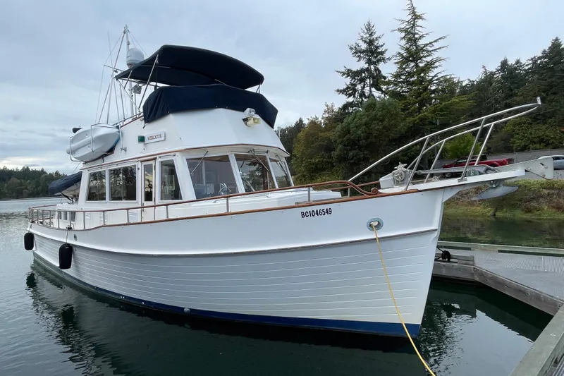 Mercator Yacht Photos Pics 1985 Grand Banks 42 Classic yacht docked in serene waters, surrounded by lush greenery.