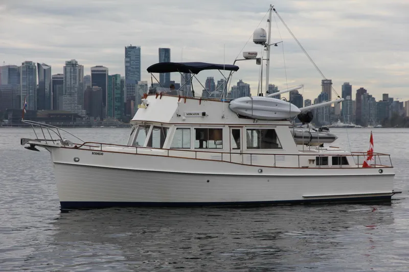 Mercator Yacht Photos Pics 1985 Grand Banks 42 Classic yacht on water with city skyline backdrop.