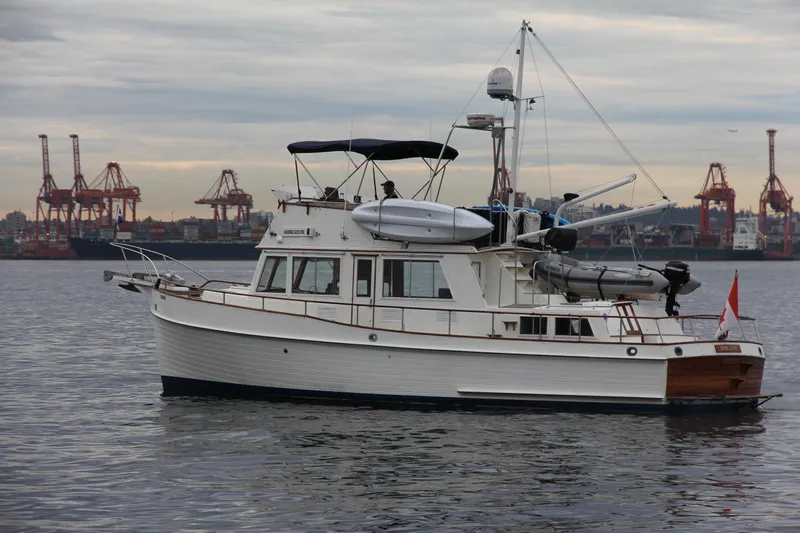 Mercator Yacht Photos Pics 1985 Grand Banks 42 Classic yacht on calm water near industrial port.