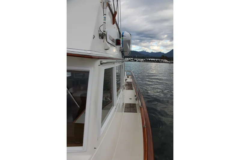 Mercator Yacht Photos Pics 1985 Grand Banks 42 Classic yacht on calm water with mountainous backdrop.