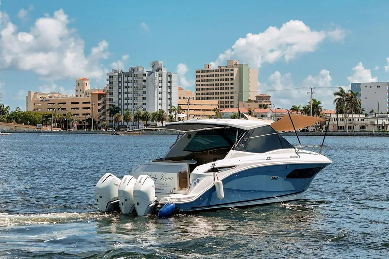 Lady Iryna Yacht Photos Pics 2022 Sea Ray Sundancer 320 Outboard cruising near urban waterfront skyline.