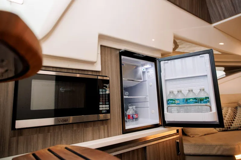 Lady Iryna Yacht Photos Pics 2022 Sea Ray Sundancer 320 Outboard interior with microwave and open mini fridge.