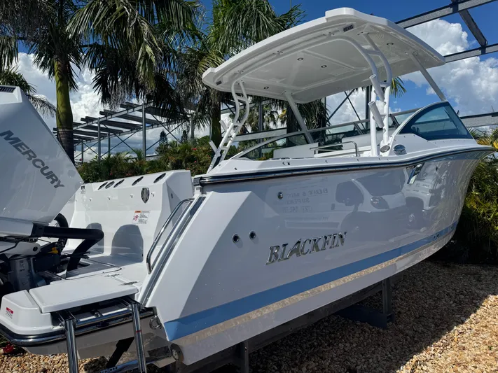  Yacht Photos Pics 2026 Blackfin 272 DC boat with Mercury engine, parked outdoors under palm trees.