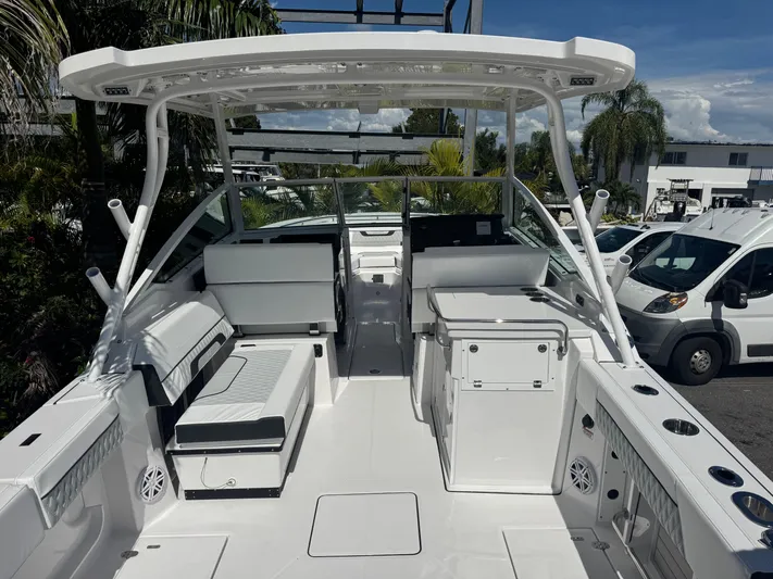  Yacht Photos Pics 2026 Blackfin 272 DC boat interior with seating, storage, and canopy in a sunny marina.