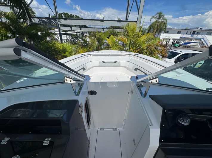  Yacht Photos Pics 2026 Blackfin 272 DC boat interior with open deck and lush greenery background.