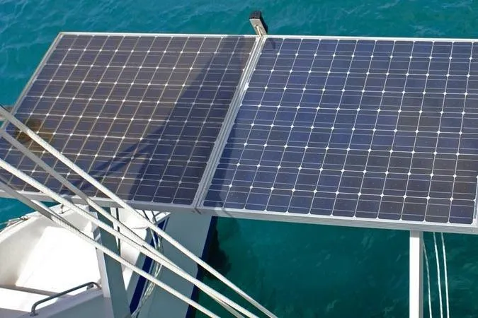 Delphine Yacht Photos Pics Solar panels on a 2003 Outremer 45 catamaran, floating on clear blue water.