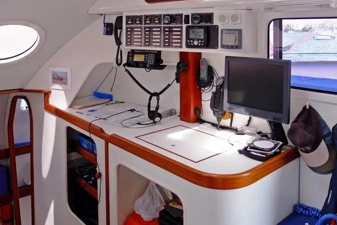 Delphine Yacht Photos Pics Navigation station inside a 2003 Outremer 45 catamaran, featuring communication equipment and a computer.