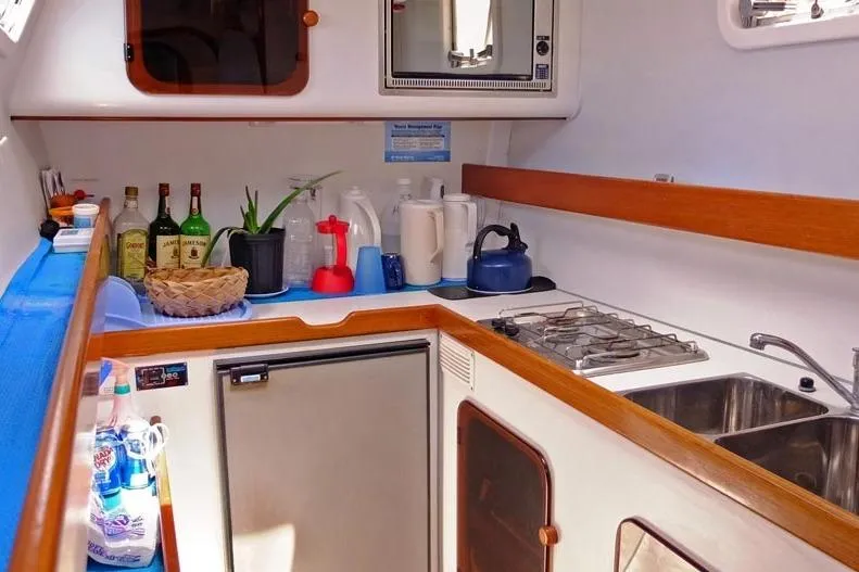 Delphine Yacht Photos Pics Compact kitchen in a 2003 Outremer 45 yacht, featuring stove, sink, and storage.