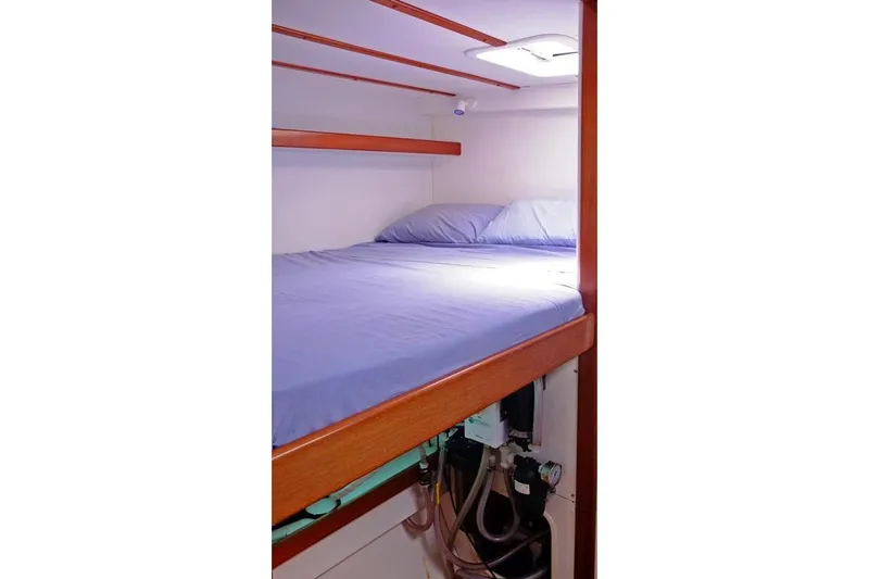 Delphine Yacht Photos Pics Interior cabin of 2003 Outremer 45 sailboat with cozy bed and wooden accents.