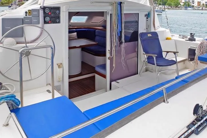 Delphine Yacht Photos Pics 2003 Outremer 45 yacht interior with blue seating and steering wheel, docked by the water.