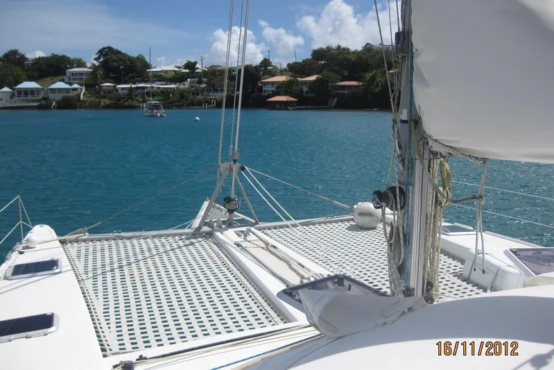 Delphine Yacht Photos Pics Outremer 45 catamaran sailing in a serene bay, 2003 model.