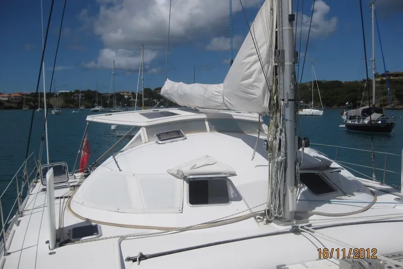 Delphine Yacht Photos Pics Outremer 45 catamaran from 2003 docked in a scenic marina.