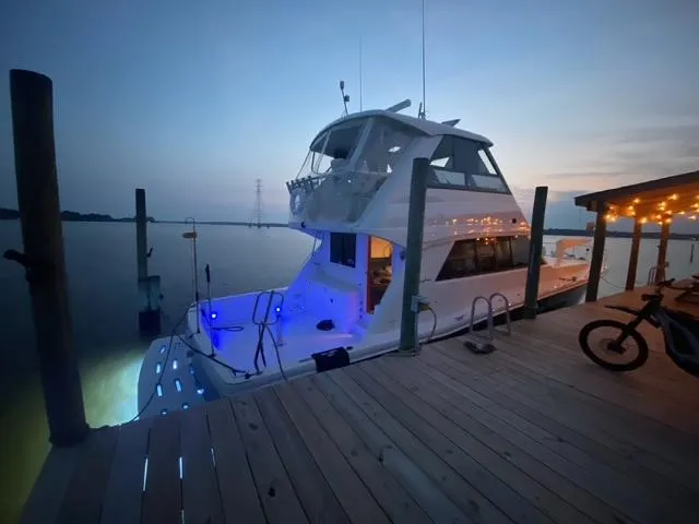 All Hans In Yacht Photos Pics 1999 Riviera SF yacht docked at sunset with blue lights illuminating the deck.